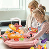 A young girl plays with an orange interactive kitchen sink toy featuring running water and a fishing game.