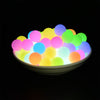 A bowl filled with glowing silicone beads of various colors including pink, blue, yellow, and green.