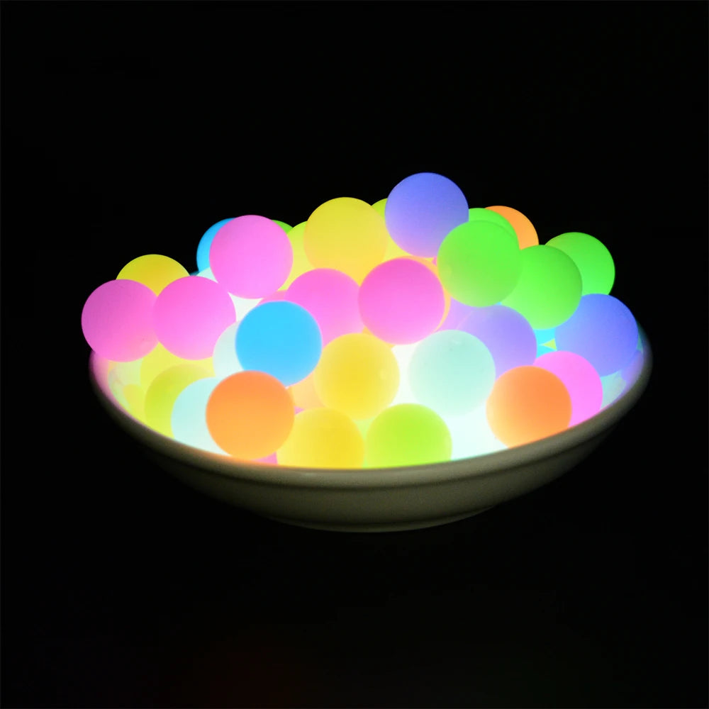 A bowl filled with glowing silicone beads of various colors including pink, blue, yellow, and green.