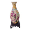 A ceramic flower vase painted in yellow and pink with blue accents, featuring a 3D puzzle design.
