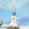 A white Toothless Dragon keychain with movable wings and glowing eyes resting on a snowy rock.