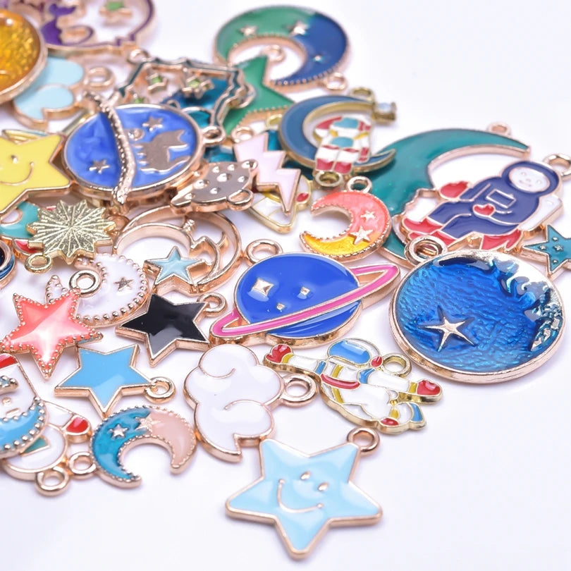 Assortment of gold-tone enamel charms featuring celestial shapes like moons, stars, and planets for jewelry making