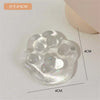 A clear, squishy cat paw shaped stress relief toy with multiple indentations and glitter inside.