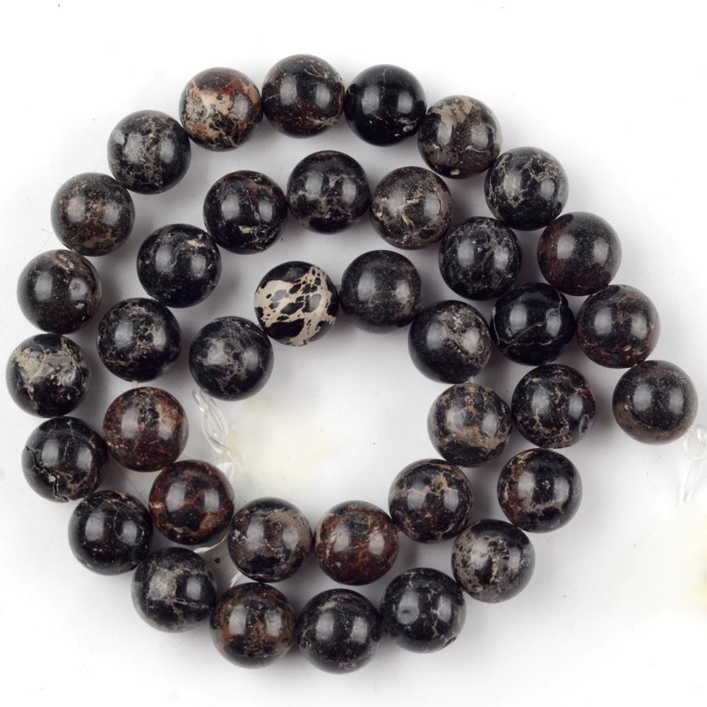 A collection of dark, speckled natural sea sediment jasper and turquoise beads for jewelry making.