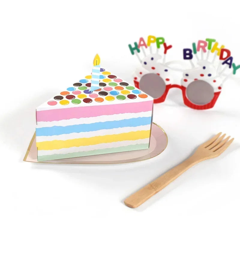 A colorful layer cake with a candle, surrounded by party decorations and a wooden fork.