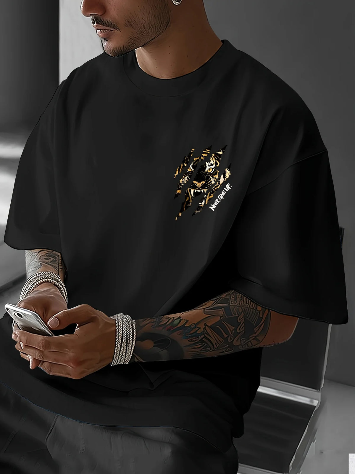 A man wearing a black graphic cotton t-shirt featuring a tiger claw design and the text Never Give Up.