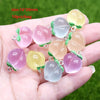 A hand holds several translucent pink and yellow sunflower-shaped resin charms for jewelry making.