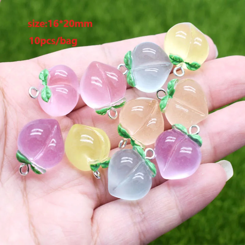 A hand holds several translucent pink and yellow sunflower-shaped resin charms for jewelry making.