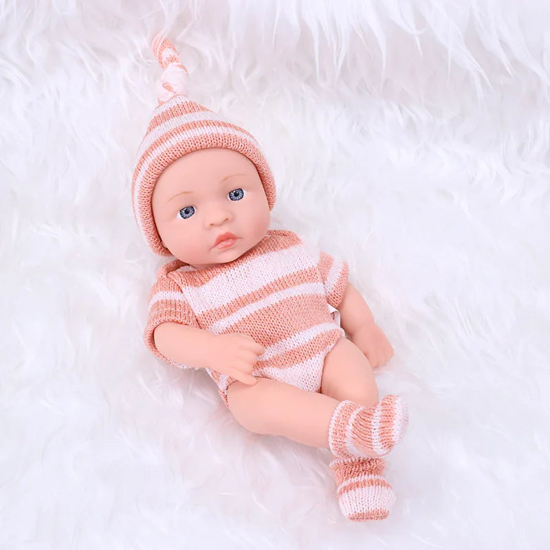 A realistic soft vinyl reborn baby doll wearing a striped knit outfit and matching hat, lying on white fur.