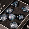 A set of handmade liquid core polyhedral dice with a galaxy finish displayed in a metal tray.