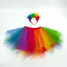 A colorful rainbow tulle tutu skirt and matching feather headband displayed against a white background.