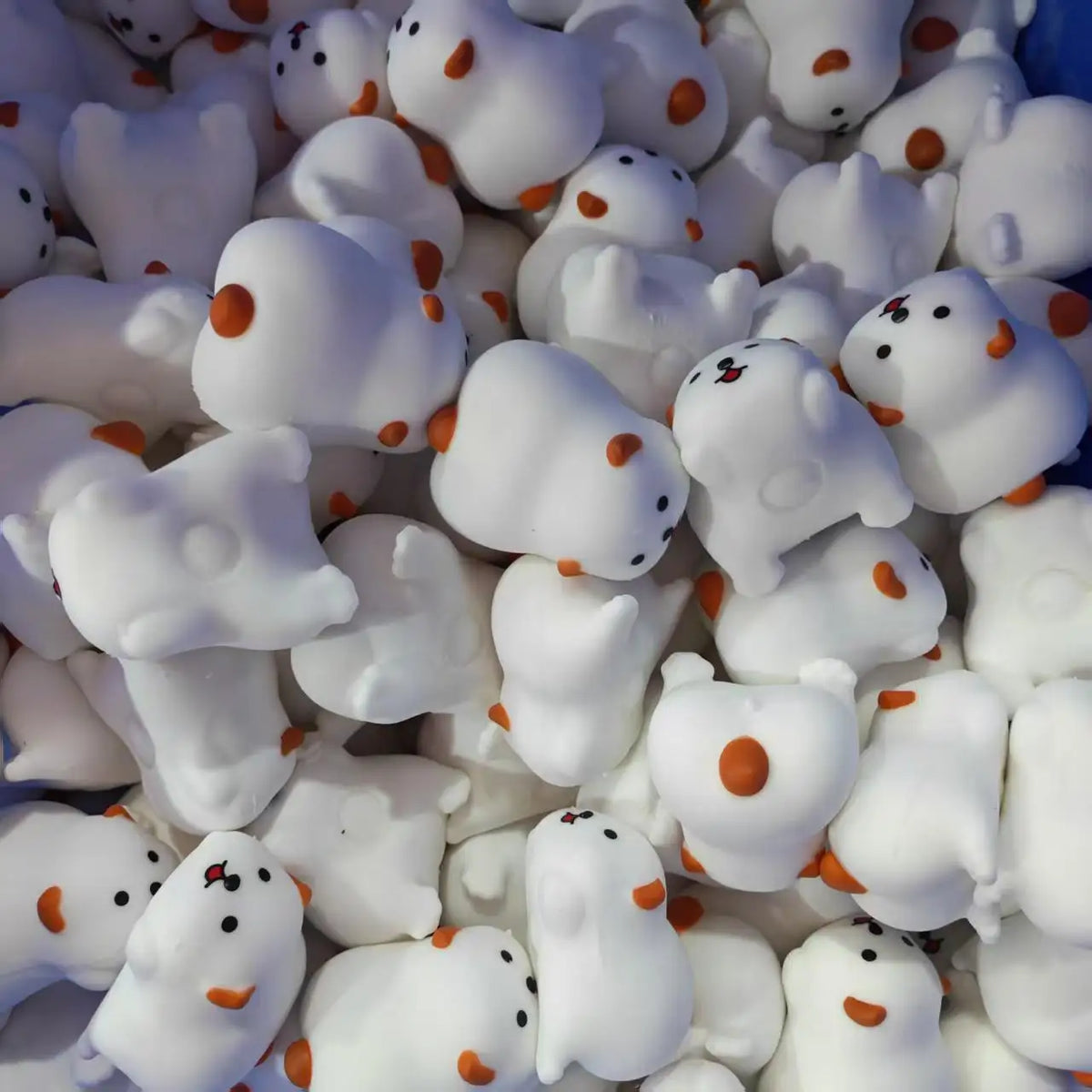 A close-up view of many white and orange cute dog noodle stress relief squishy toys.