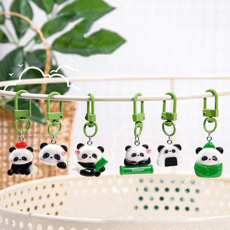 A collection of adorable panda keychains and charms hanging on a light-colored wooden rack.