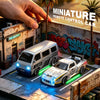Un modèle de voiture télécommandée miniature avec une camionnette argentée et une voiture de sport blanche sur un diorama.