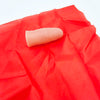 Un doigt rose pâle est visible sur un tissu de soie rouge, utilisé pour un tour de magie.