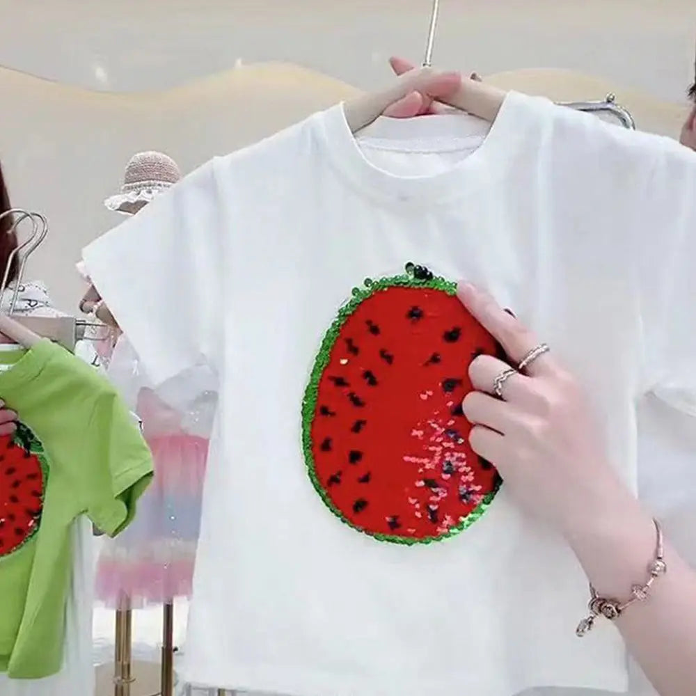 A white t-shirt featuring a large, embroidered watermelon design with black seeds and green rind details.