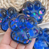 A hand holds a blue translucent silicone paw print fidget toy with iridescent glitter.
