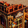 A miniature wooden dollhouse structure featuring an ornate pavilion with arched windows and decorative trim.