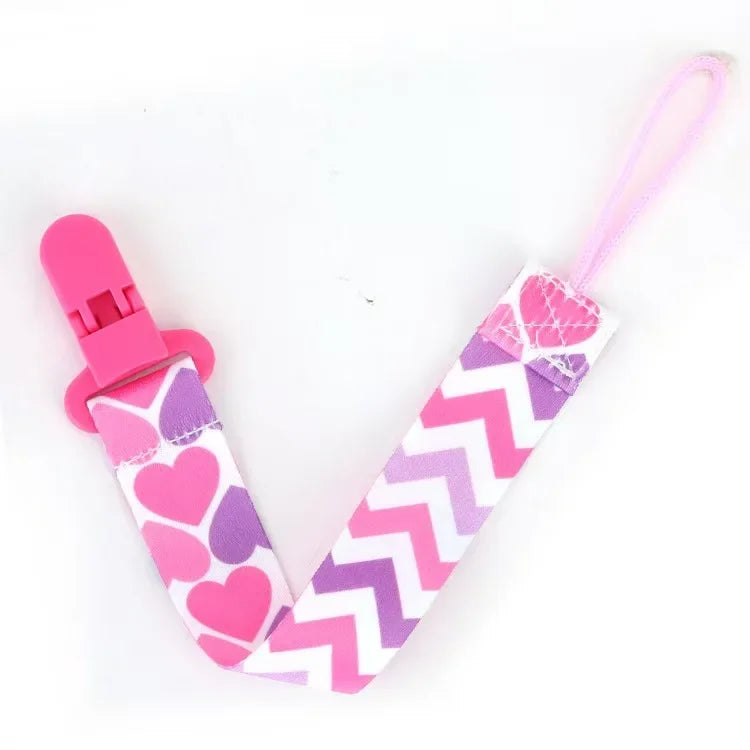 Pink and purple pacifier clips with heart and chevron prints on a pink strap