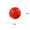 A round, red watermelon ice sand squeeze toy with visible pits and a crunchy texture.
