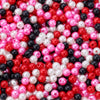 A close-up of colorful imitation pearl beads in various shades of pink, red, white, and black.