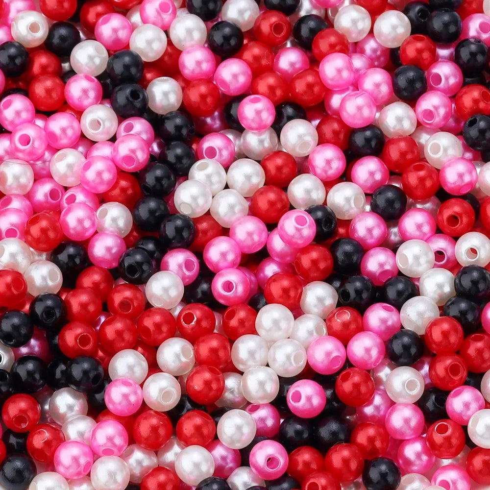 A close-up of colorful imitation pearl beads in various shades of pink, red, white, and black.