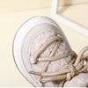 Close-up of a beige baby winter snow boot with braided laces and plush lining
