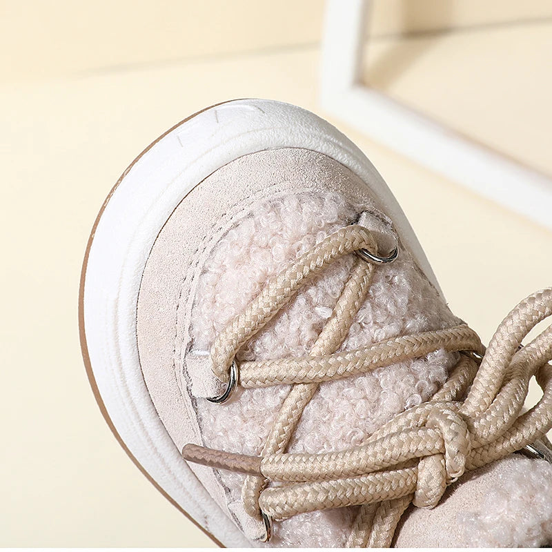 Close-up of a beige baby winter snow boot with braided laces and plush lining