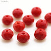 A collection of bright red, round crystal glass beads used for jewelry making.