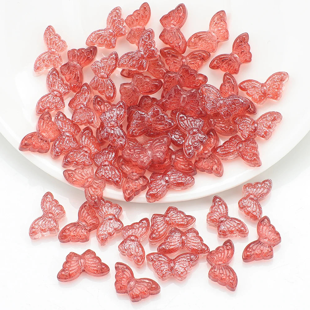 A pile of pink and reddish glass butterfly beads for jewelry making