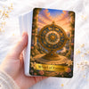 A hand holds a tarot card depicting the Wheel of Fortune with an ornate golden design against a sunset sky.