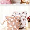 Two beige and pink reusable waterproof baby wet bags with bear patterns are displayed on a white surface.