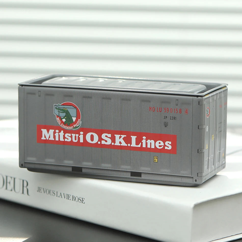 A silver industrial iron storage box labeled Mitsui O.S.K.Lines resting on a white book.