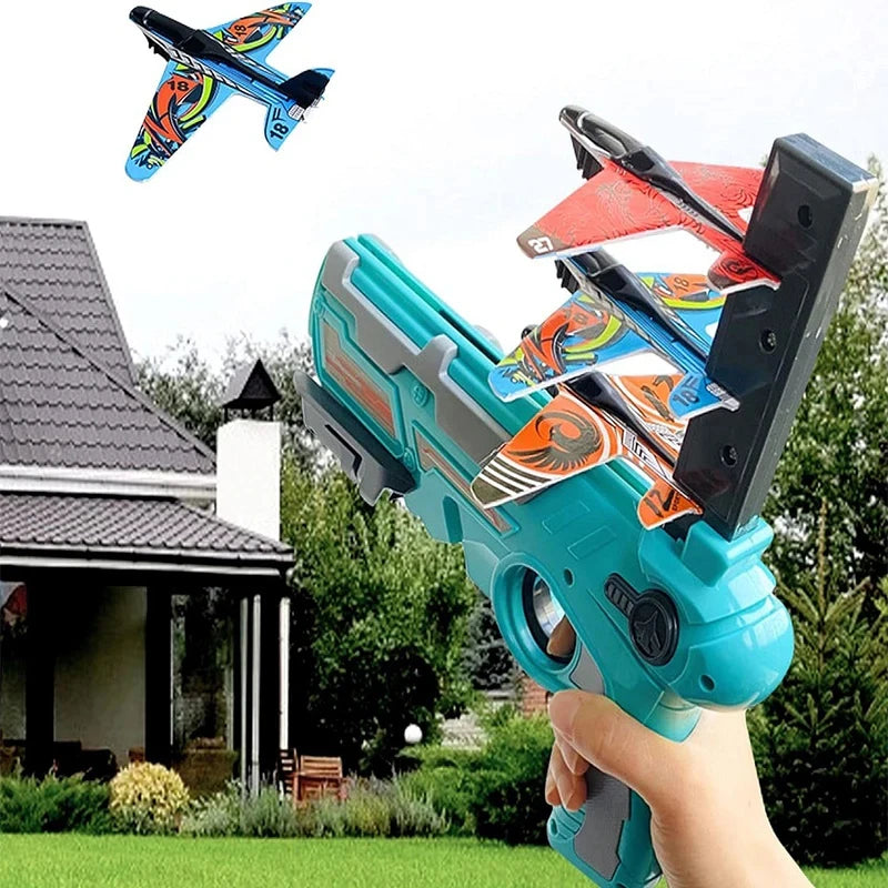 A hand holds a blue airplane launcher toy with three foam planes, set against a backyard background.
