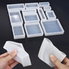 A collection of white geometric resin casting molds and a hand holding one mold.