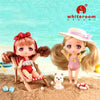 A cute doll with pink hair and a straw hat is shown next to a small white dog on a sandy beach background.