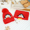 A red knit penguin hat and matching scarf set with white accents displayed on a white surface.