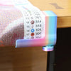 A close-up of an adjustable diamond painting canvas stand with a table clamp and roller, featuring a colorful plastic frame.