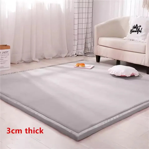 A thick gray foam baby play mat is shown indoors on a light wooden floor.