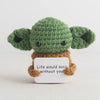 Handmade crochet pocket hug doll with green body and brown limbs featuring an inspirational slogan tag.