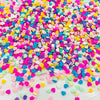 A close-up of colorful polymer clay star and heart sprinkles in various shades of pink, blue, yellow, and green.