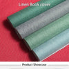 A showcase of various shades of linen book cover fabric rolled out on a red surface.