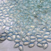 Clear blue water drop glass beads scattered on a white surface for jewelry making