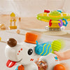 A white cartoon baby rattle toy with blue wheels and orange accents is shown gliding across a light surface.