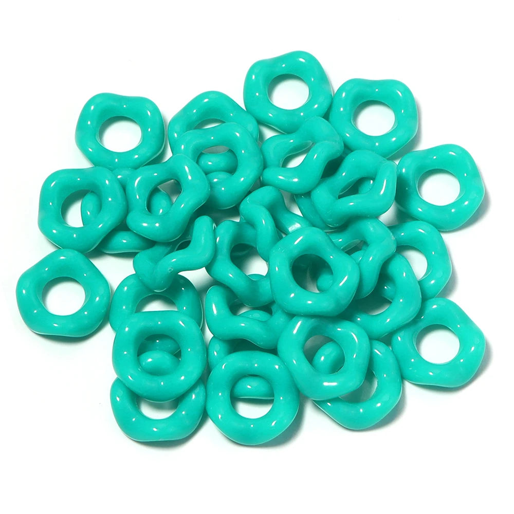 A pile of light turquoise acrylic doughnut spacer beads for jewelry making