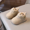 A pair of beige quilted toddler winter snow boots with soft soles and Velcro closures resting on a light surface.