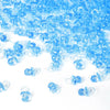 A pile of small, translucent blue acrylic pacifier party favors for baby shower decorations.