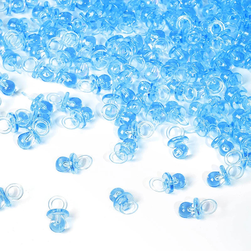 A pile of small, translucent blue acrylic pacifier party favors for baby shower decorations.