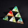 A set of seven triangular resin dice showing numbers 1 through 6 and a 4, arranged diagonally on a black background.