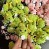 A pile of handmade crochet dinosaur keychains in lime green and pink colors.